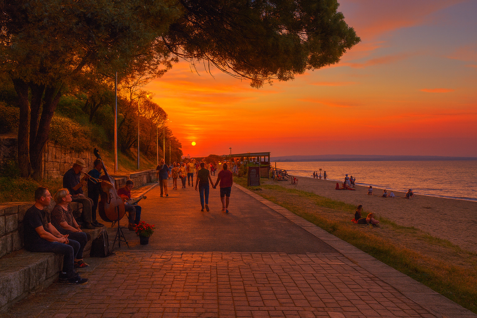 Strandpromenade in Burgas am Abend mit Jazzband, Zuhörern, Spaziergängern und Sonnenuntergang über dem Meer.