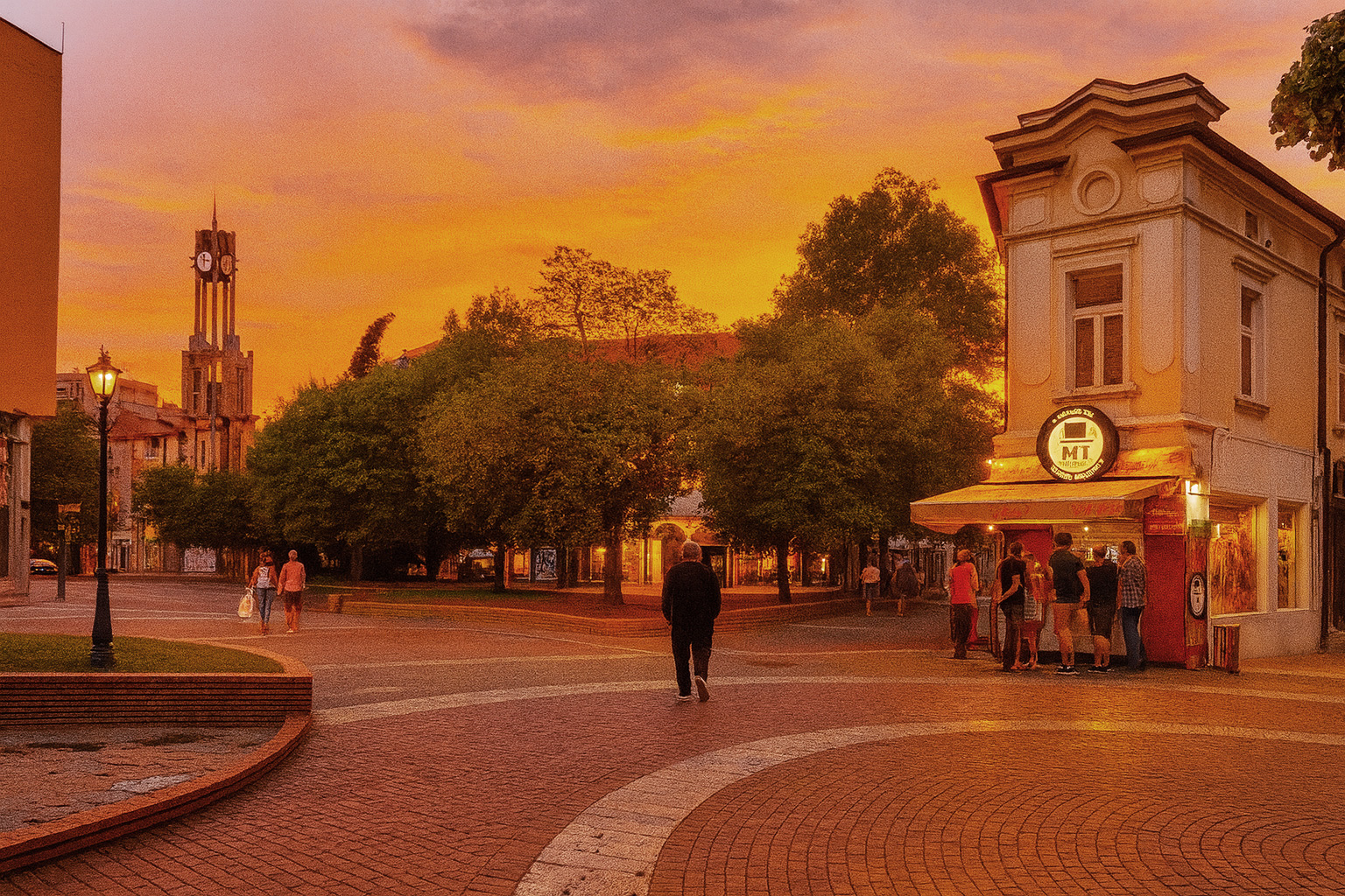 Altstadt von Chaskowo am Abend mit beleuchtetem Imbiss, wartenden Personen und Sonnenuntergangshimmel über dem Platz.