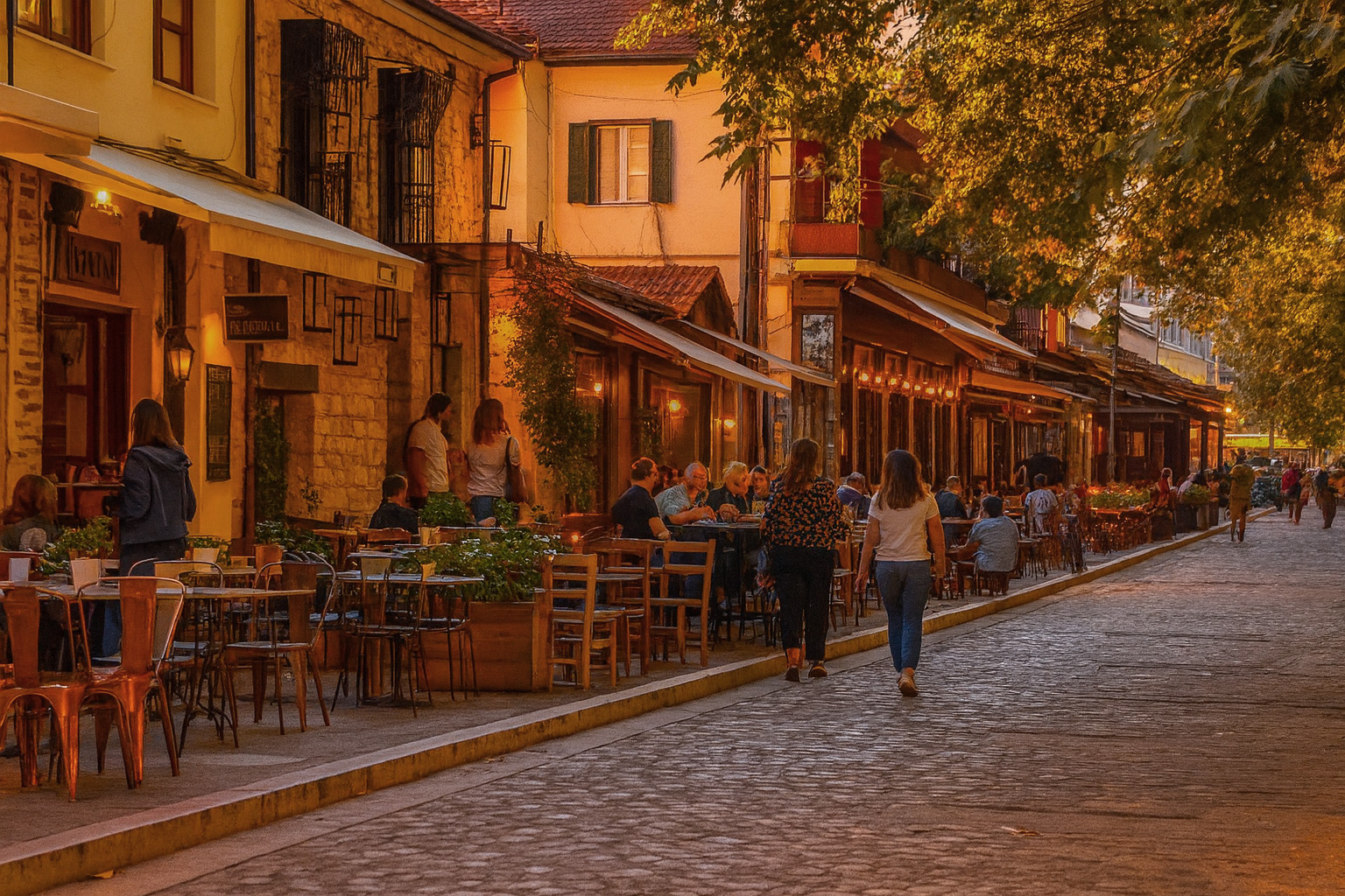 Abendstimmung in der Fußgängerzone von Ioannina mit beleuchteten Straßencafés und Spaziergängern auf dem Kopfsteinpflasterweg.