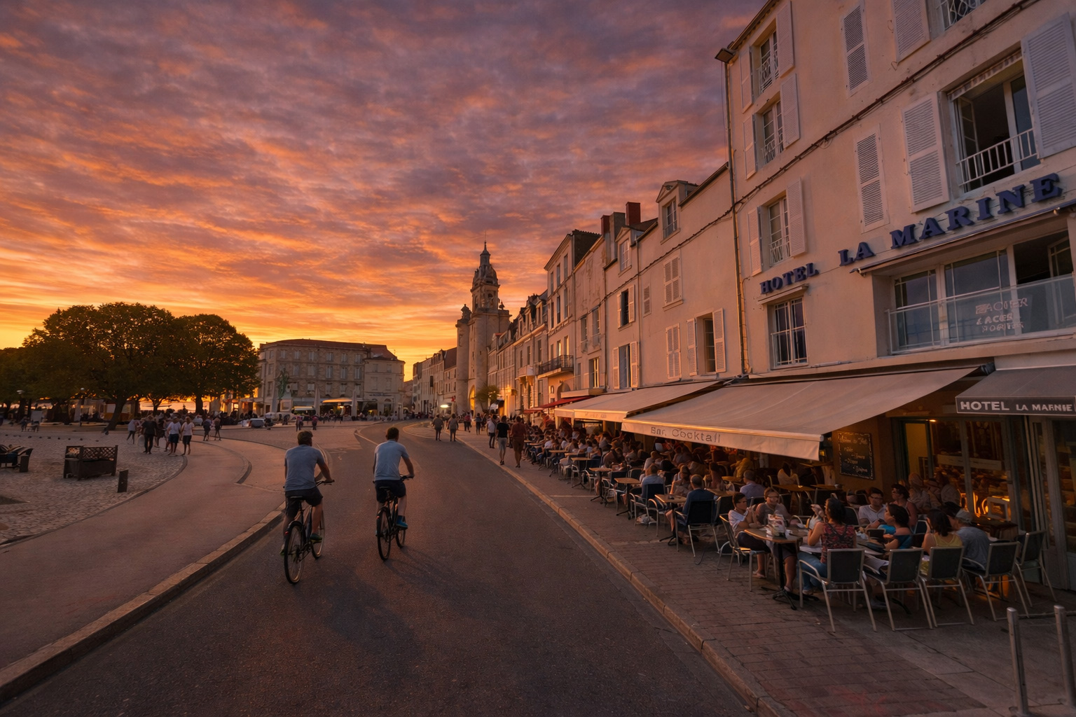Abendstimmung am Quai Duperré mit warm beleuchtetem Straßencafé rechts unter Markisen, Spaziergängern entlang der Promenade, zwei Fahrradfahrern auf der Fahrbahn, leuchtenden Fenstern der historischen Fassaden und dramatischem Himmel bei Sonnenuntergang
