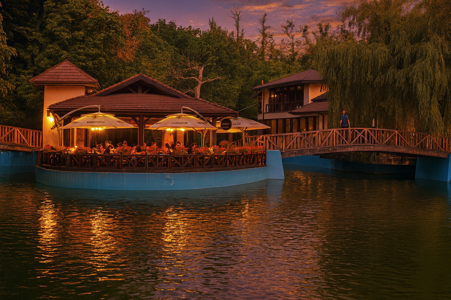 Beleuchtetes Café-Pavillon im Park von Râmnicu Vâlcea am Abend mit warmem Licht, Spiegelung im Wasser und Spaziergänger auf der Holzbrücke.