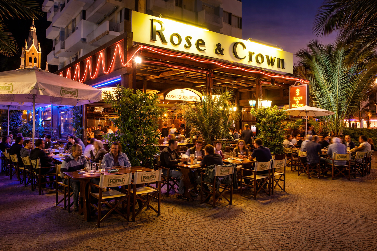 Abendliche Szene am Rose & Crown Pub in der Viale Regina Elena in Rimini mit beleuchtetem Straßencafé, sitzenden Gästen an Holztischen, warmem Licht, Palmen und lebendiger Atmosphäre bei Einbruch der Dämmerung.