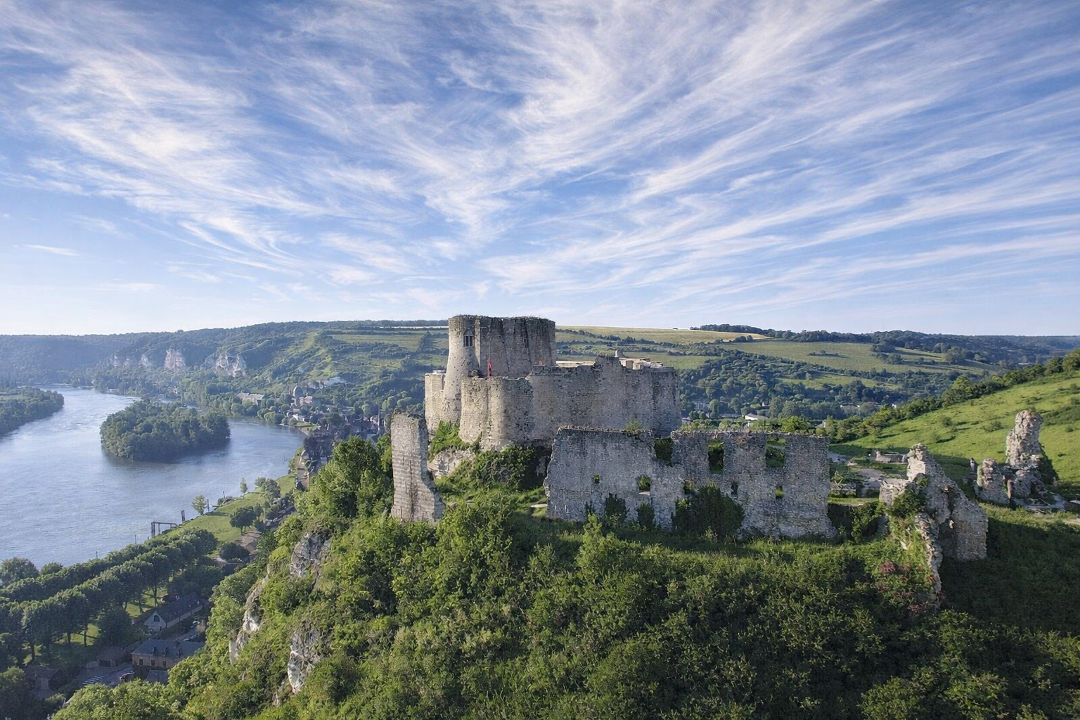 Ruinen von Château Gaillard auf einem grünen Felsrücken über einer breiten Flussschleife der Seine, mit weitem Blick über Tal, Dörfer und Hügel unter einem hohen Himmel mit feinen Schleierwolken