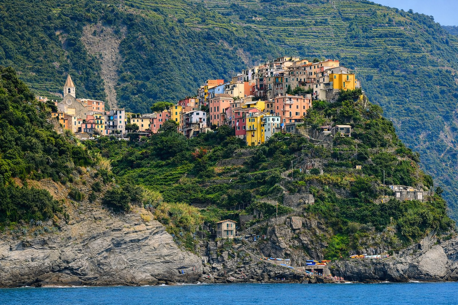 Panorama von Corniglia zu den Cinque Terre mit buten Häusern an den Felsen direkt am Meer.
