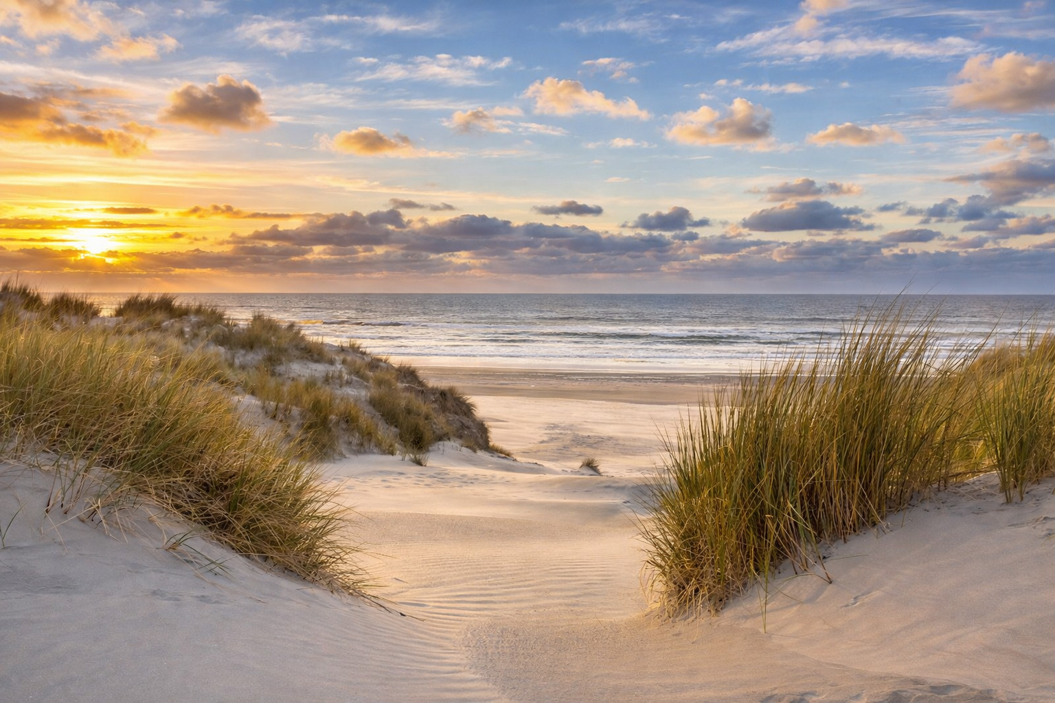 Weite Dünenlandschaft an der Nordsee mit feinem, windgeformtem Sand und Strandhafer, ein natürlicher Pfad führt zwischen den Dünen zum Meer, während warmes Sonnenlicht und leicht veränderte Wolken den Himmel über den sanften Wellen prägen