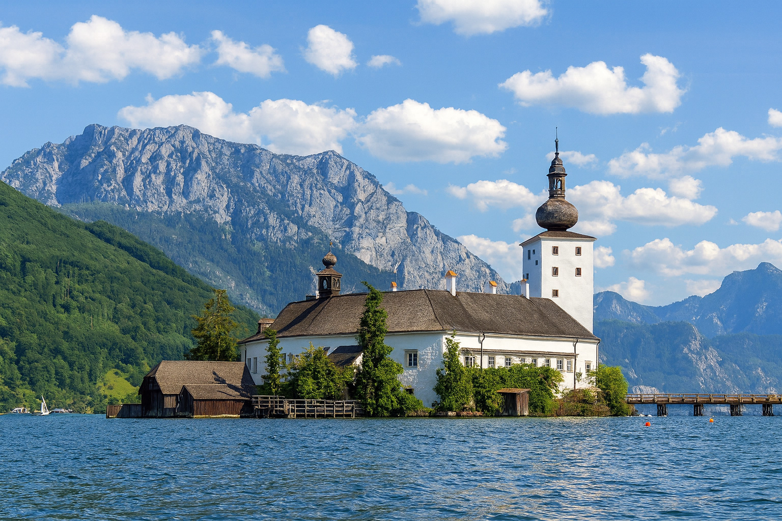 Schloss Ort im Traunsee vor den Bergen mit malerischen weiß-grauen Wolken bei sonnigem Wetter