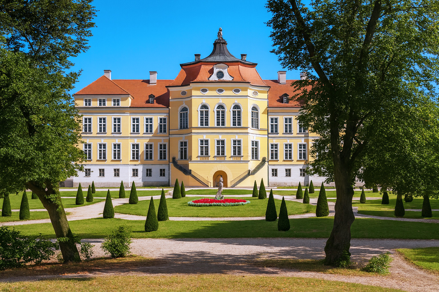 Schloss Rogalin in Polen mit barocker Fassade und Gartenanlage unter klarem blauen Himmel im besten Sonnenlicht.