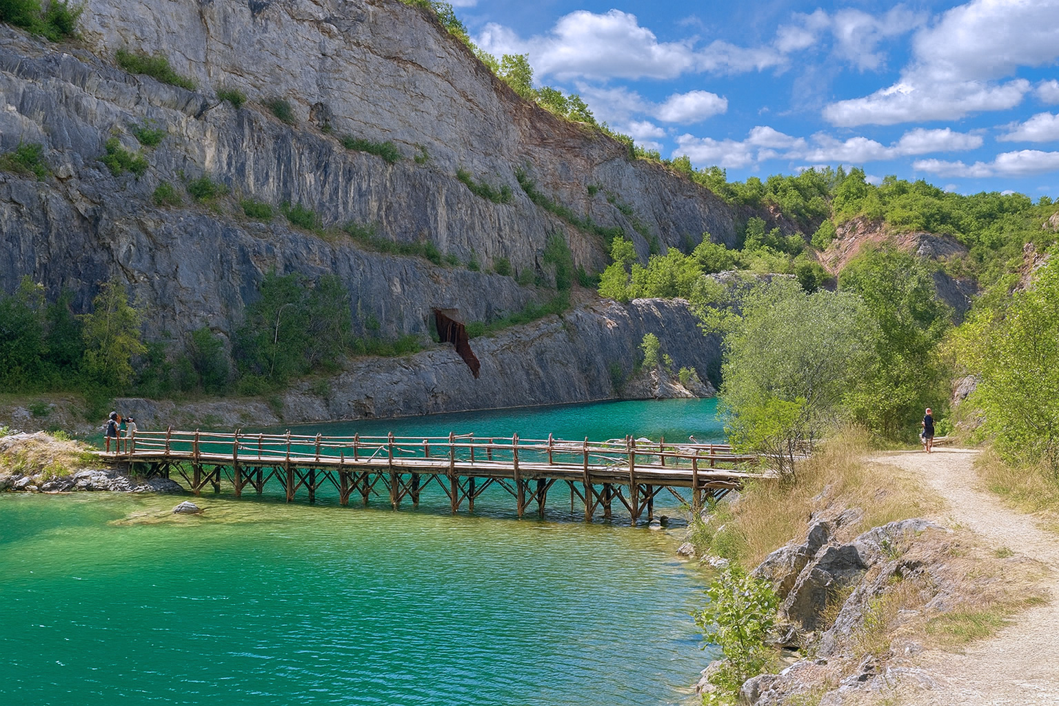 Velká Amerika Schlucht mit türkisfarbenem Wasser, Holzbrücke, Felswänden und malerischen weiß-grauen Wolken