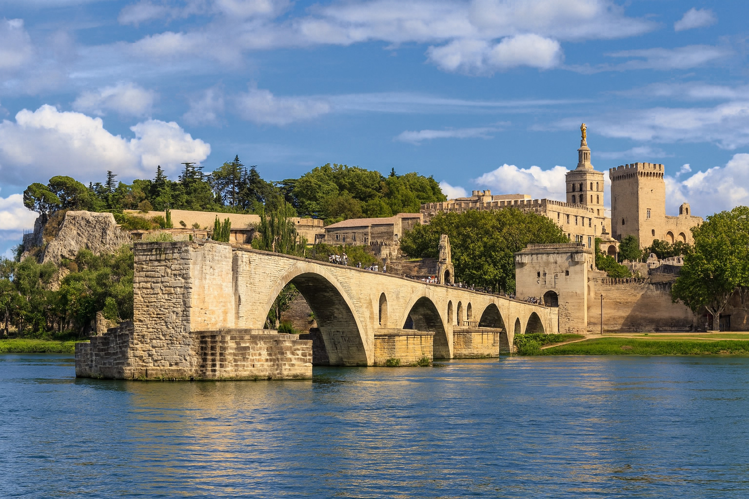 Panorama der Pont Saint-Bénézet Brücke in Avignon mit dem Papstpalast unter malerischen weiß-grauen Wolken im besten Sonnenlicht.