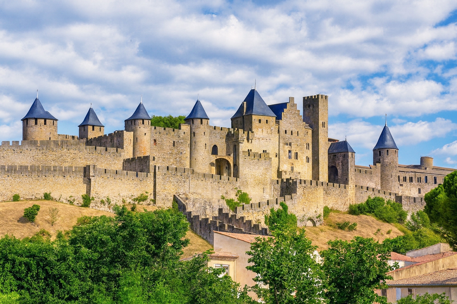 Die mittelalterlichen Festungsmauern der Altstadt von Carcassonne unter malerischen weiß-grauen Wolken im besten Sonnenlicht.