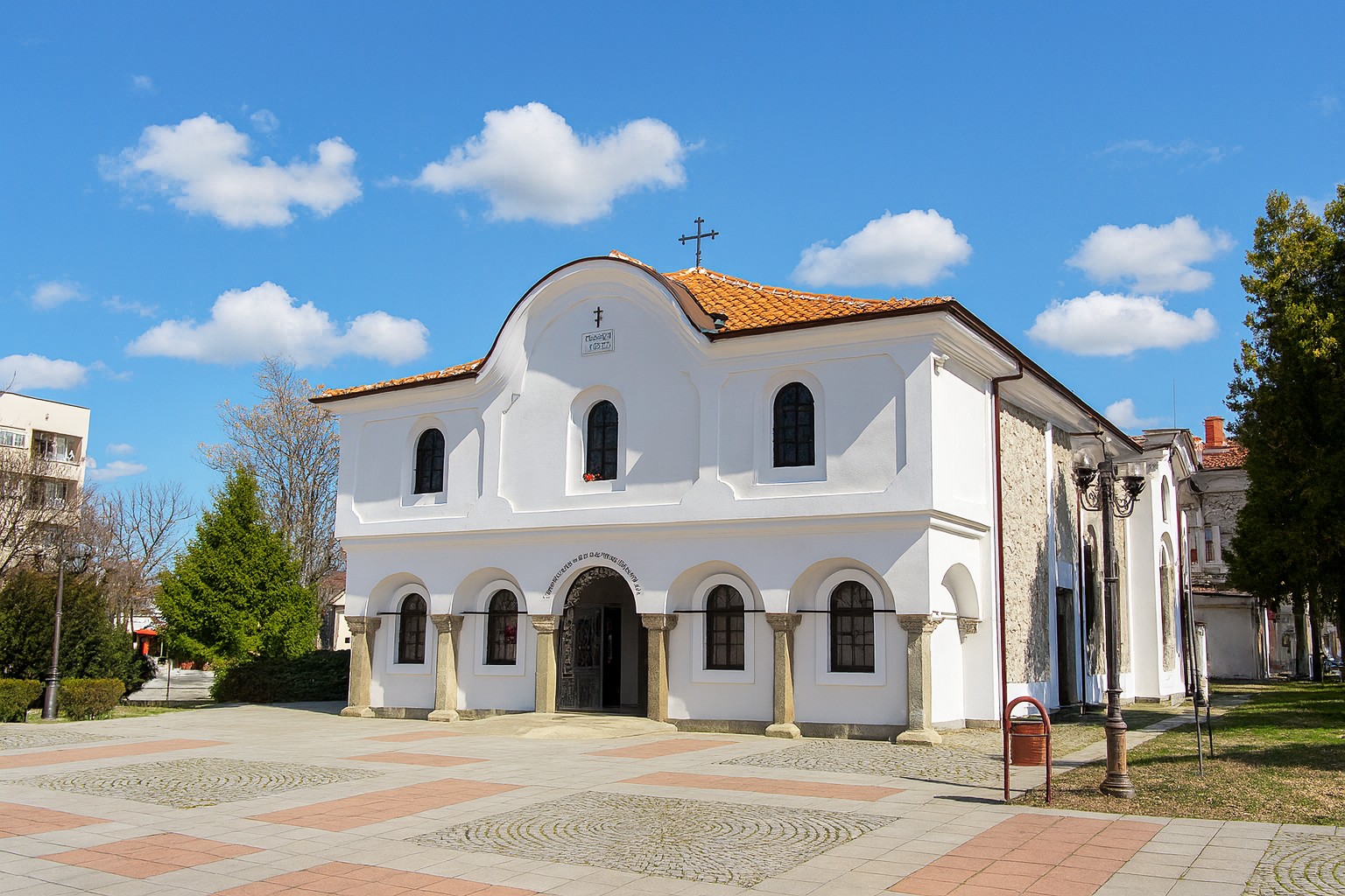 Sweti-Dimitar-Kirche in Elchowo mit weißer Fassade, rotem Ziegeldach und blauem Himmel mit weißen Wolken.