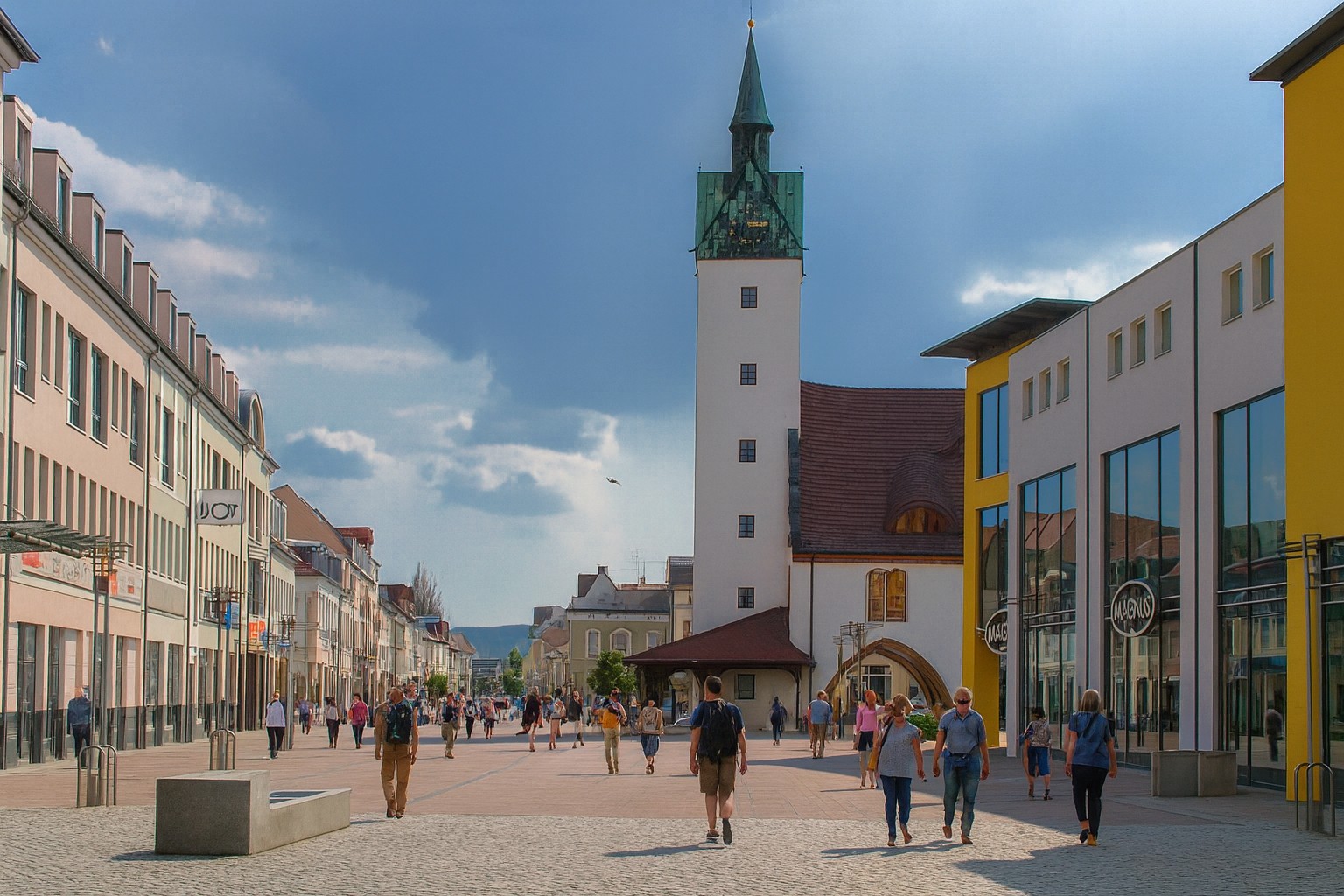 Marktplatz in Fürstenwalde in Deutschland mit dem markanten Turm im Hintergrund, bei Sonnenschein und malerischen Wolken, belebt mit Spaziergängern.