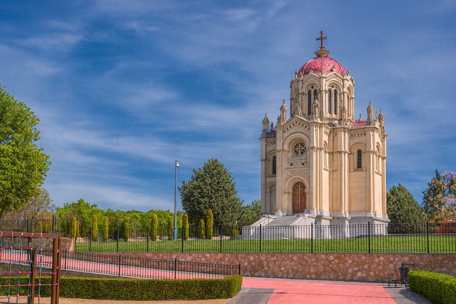 Panteón de la Duquesa de Sevillano in Guadalajara mit seiner prachtvollen Kuppel und neogotischer Fassade bei strahlendem Sonnenlicht und malerischen weiß-grauen Wolken.