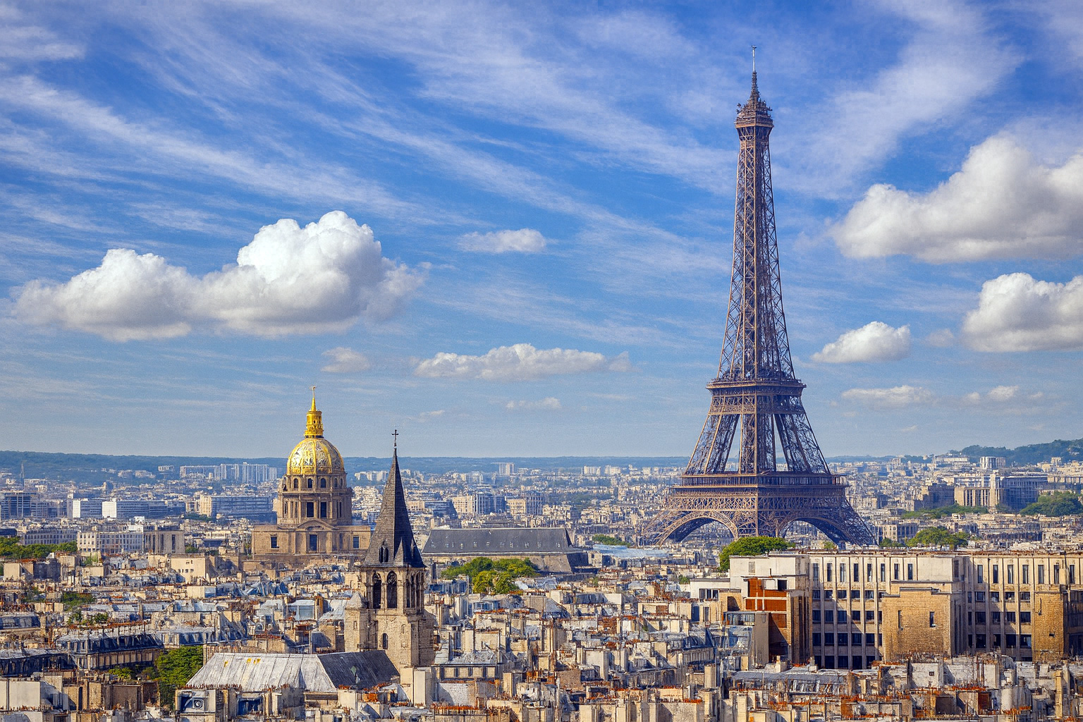 Panorama über den Dächern von Paris mit dem Eiffelturm und der goldenen Kuppel von Les Invalides unter einem Himmel mit Zirrus- und Cumuluswolken bei Sonnenlicht.