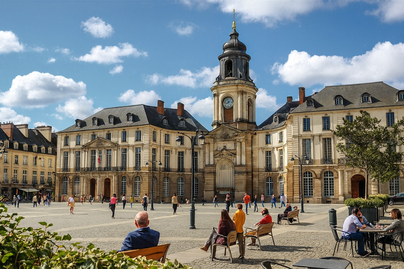 Sonniger Place de la Mairie in Rennes mit dem Hôtel de Ville, mit Spaziergängern und Personen auf Bänken und im Straßencafé, umgeben von malerischen weiß-grauen Wolken am blauen Himmel.