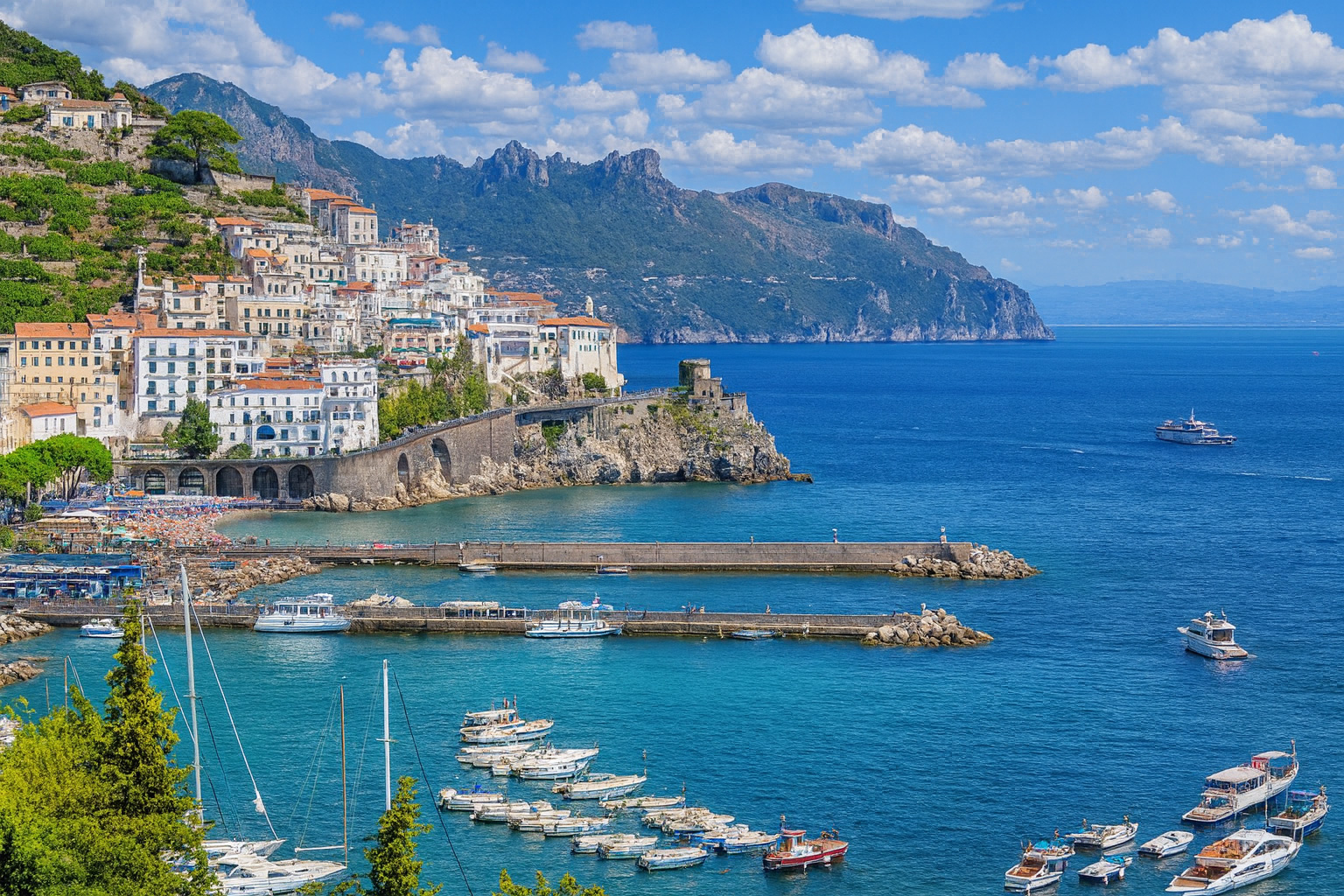 Panorama von Salerno an der Amalfiküste mit bunten Häusern, Yachthafen, tiefblauem Meer und malerischen weiß-grauen Wolken im besten Sonnenlicht.