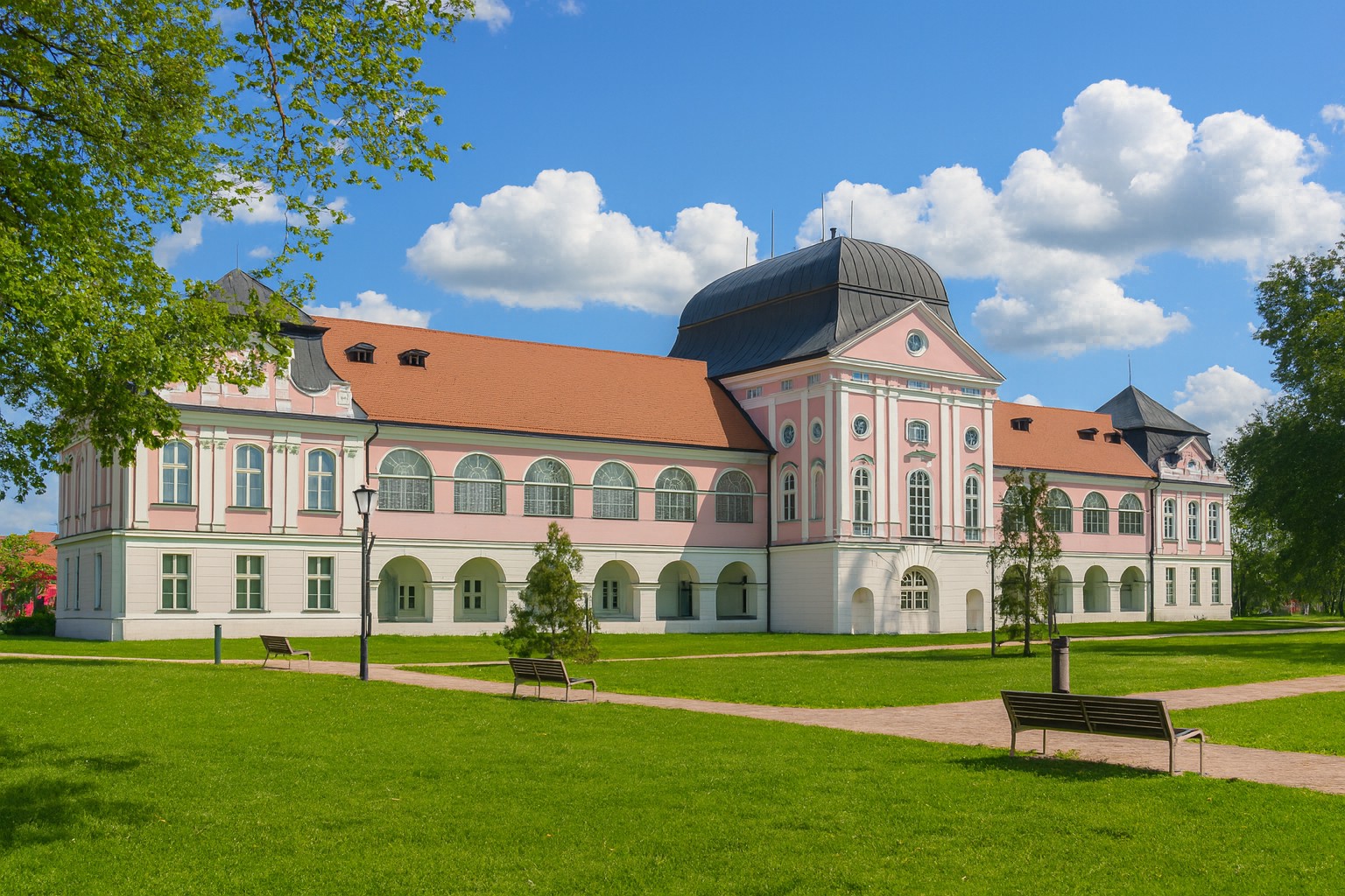 Schloss von Virovitica in Kroatien mit barocker Architektur, rosafarbener Fassade und Sommerpark bei blauem Himmel