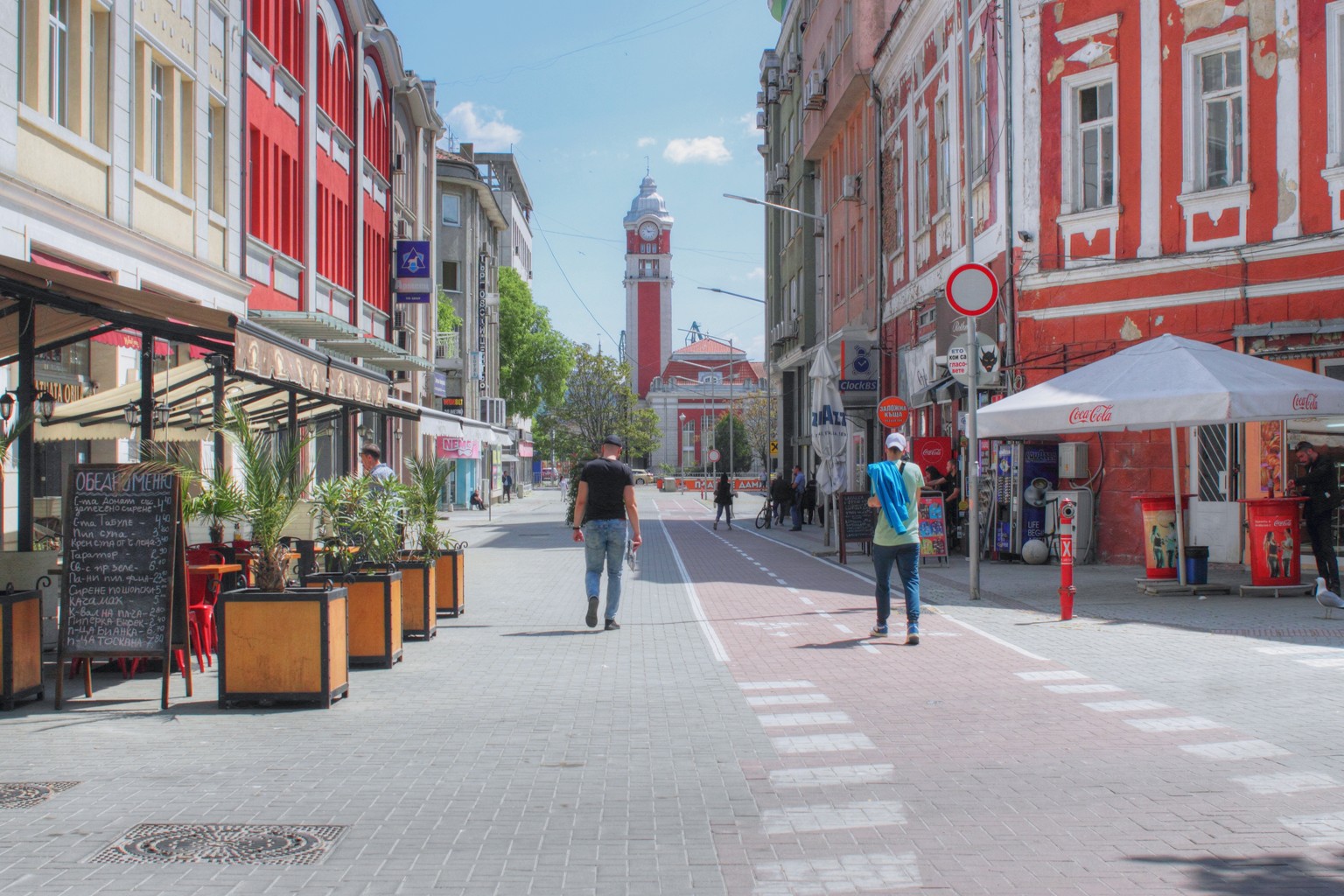 Die Fußgängerzone in Warna und im Hintergrund der Turm vom Bahnhof in Sonnenschein.
