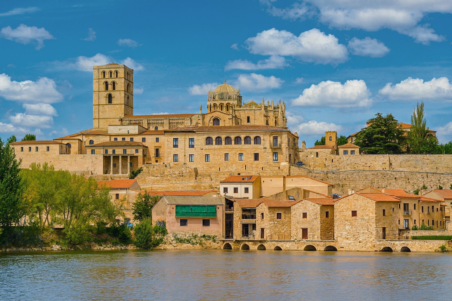 Panorama der Altstadt von Zamora mit der Kathedrale von Zamora im Hintergrund, gesehen vom Fluss Duero bei Sonnenlicht und unter malerischen weiß-grauen Wolken.