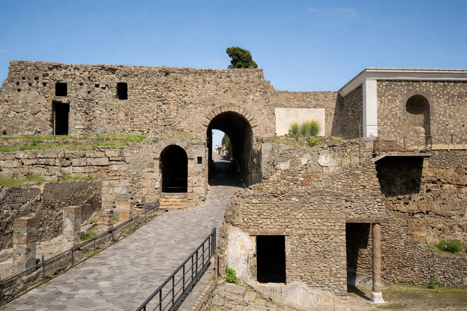 Porta Marina mit antikem Stadttor und angrenzender Stadtmauer von Pompei, Blick auf den gepflasterten Zugangsweg und die massiven Steinbauten unter klarem Himmel