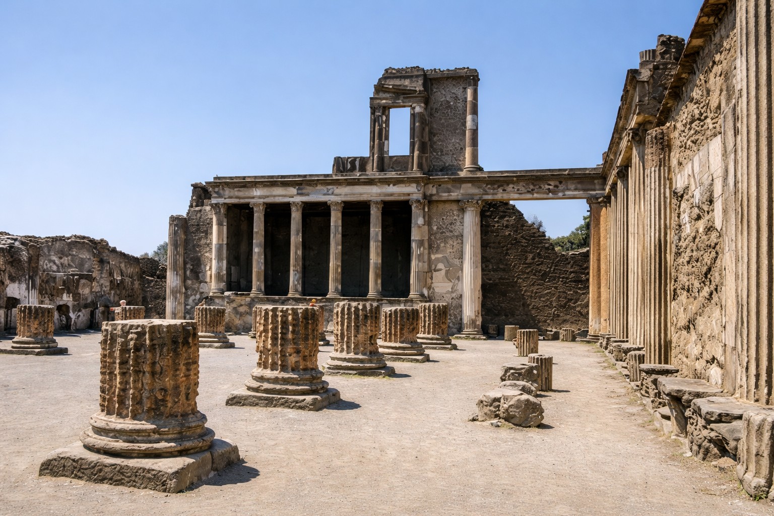 Römische Basilika von Pompei mit Säulenreihen und monumentaler Portikus, Blick über den offenen Platz auf die erhaltenen Steinstrukturen unter klarem Himmel