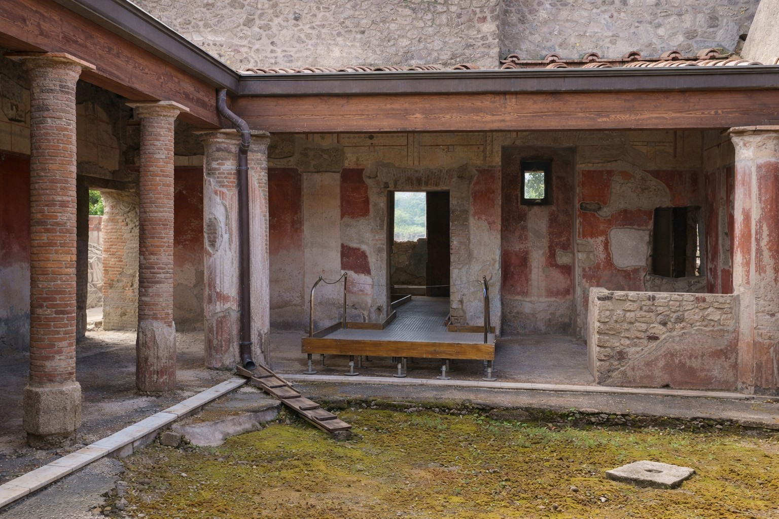Innenhof der Casa della Nave Europa in Pompei mit Ziegel- und Steinsäulen, erhaltenen Wandmalereien in Rot- und Ockertönen sowie Blick auf die umlaufenden Räume eines römischen Wohnhauses