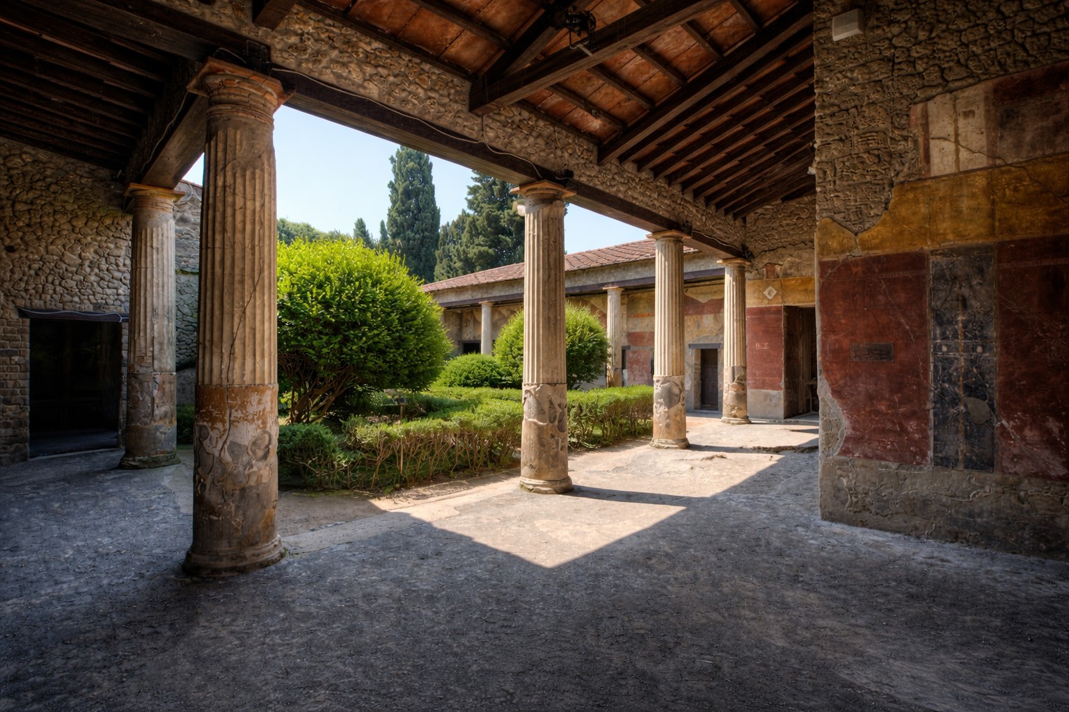 Peristylhof der Casa della Venere in Conchiglia in Pompei mit antiken Säulen, bemalten Wandflächen und gepflegtem Garten, Blick durch den überdachten Säulengang in den sonnigen Innenhof