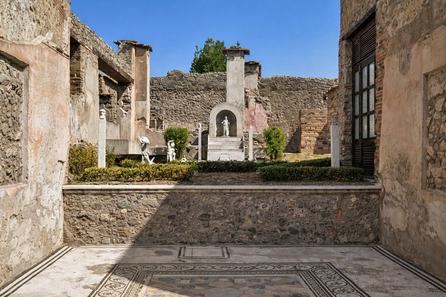 Innenhof der Casa di Marco Lucrezio an der Via Stabiana in Pompei mit zentralem Garten, steinerner Nische mit Statue, umliegenden Hausmauern und dekorativem Mosaikboden im Vordergrund