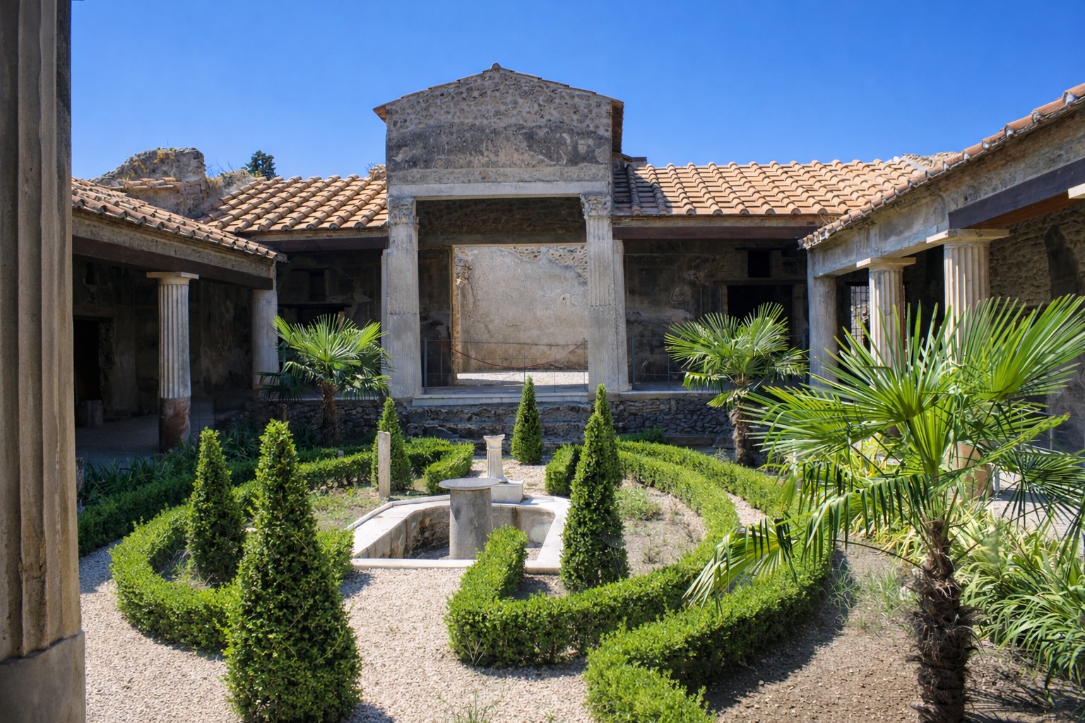 Peristylgarten der Casa degli Amorini Dorati in Pompei mit symmetrisch angelegten Buchshecken, zentralem Wasserbecken, antiken Säulenhallen und Blick auf das umgebende römische Wohnhaus unter klarem blauem Himmel